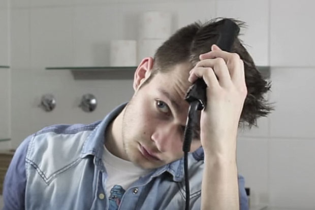 Video Mann mit dunkelbraunen Haaren glättet sich die Haare mit Haarglätter im Badezimmer