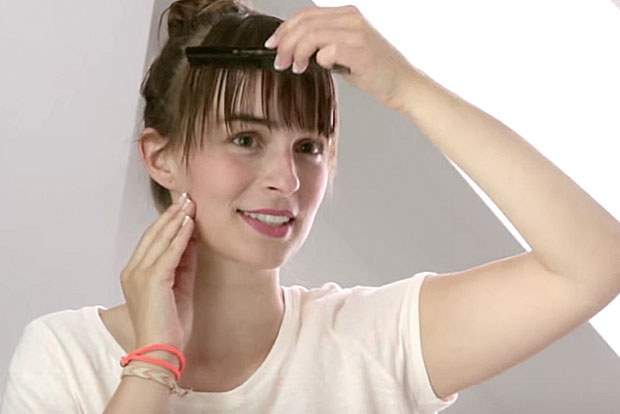 Video woman styles fringe with a comb 
