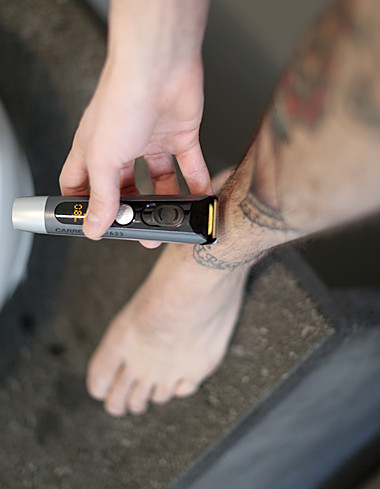 man shaves his left leg with beard trimmer No 623